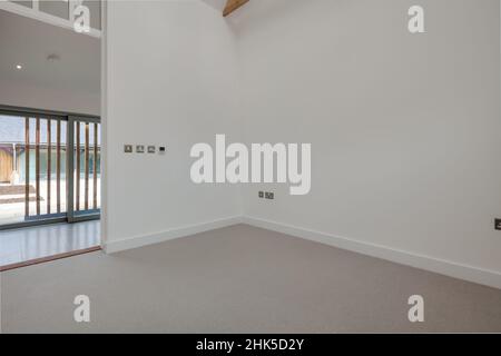 Trumpington, Cambridgeshire - Maggio 04 2017: Ingresso vuoto dipinto di bianco sala open space soggiorno in nuova casa con porta aperta e grandi porte patio Foto Stock