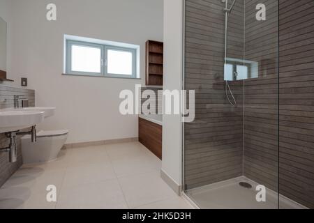 Trumpington, Cambridgeshire - Maggio 04 2017: Camera da bagno minimalista di lusso contemporaneo con doccia all'interno di una nuova casa con pareti piastrellate e dipinte di bianco Foto Stock