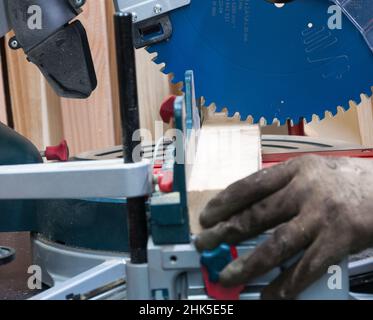 l'operaio taglia un pezzo di legno con la sega circolare. Foto Stock