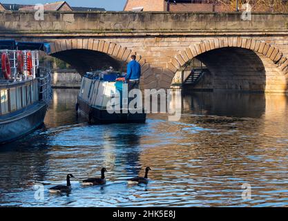 Una scena tranquilla vicino al Tamigi a Oxford, mentre una casa galleggiante passa sotto il Folly Bridge in una luminosa mattinata invernale. Questo ponte di pietra, eretto dal 1825-27, c Foto Stock