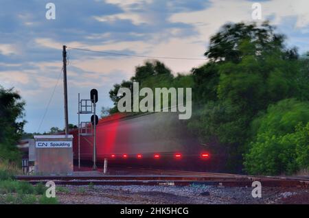 Bartlett, Illinois, Stati Uniti. Un dispositivo di fine treno appare come una serie di trattini mentre lampeggia su un treno merci, offuscato dal suo movimento. Foto Stock