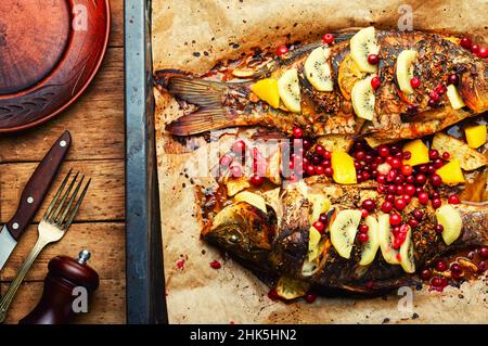 Carpa di pesce al forno con frutta e frutti di bosco in forno. Foto Stock