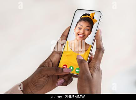 Riunione virtuale. Donna afroamericana che videochatting con la sua amica, tenendo smartphone, closeup, collage Foto Stock