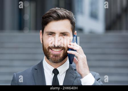 Primo piano ritratto foto di successo bearded uomo d'affari sorridente parlando al telefono Foto Stock