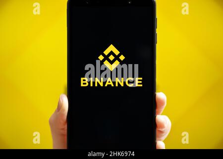 Ucraina, Odessa - 9 ottobre 2021: Tenere a mano il cellulare con l'app Binance in esecuzione sullo schermo dello smartphone con il logo Binance sullo sfondo. Binance è una piattaforma di scambio e scambio di criptovaluta Foto Stock