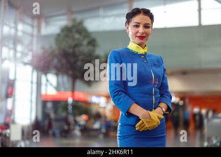 Assistente di volo donna in piedi nel terminal dell'aeroporto Foto Stock