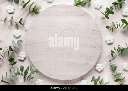 Wintertime mockup con spazio di testo su tavola rotonda in pietra circolare. Foglie e rametti di eucalipto freschi. Foto Stock