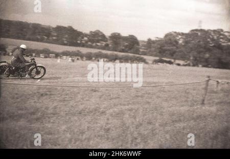1950s, storico, scrambling, un pilota maschile sulla sua moto che corre attraverso un campo collinare, Inghilterra, Regno Unito. Iniziato a Camberley, Surrey, Inghilterra nel 1920s, le biciclette usate originariamente nelle corse di fondo erano normali roadbike con poca sospensione. Foto Stock