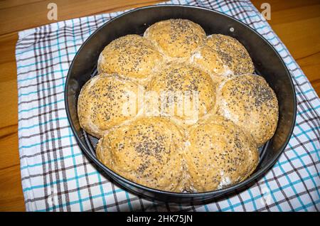 Ciambelle fresche fatte in casa cosparse di semi in una teglia da forno. Foto Stock