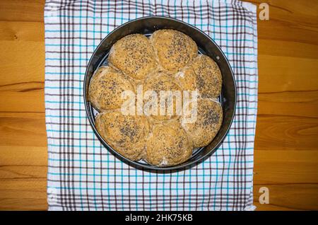 Ciambelle fresche fatte in casa cosparse di semi in una teglia da forno. Foto Stock