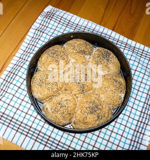 Ciambelle fresche fatte in casa cosparse di semi in una teglia da forno. Foto Stock