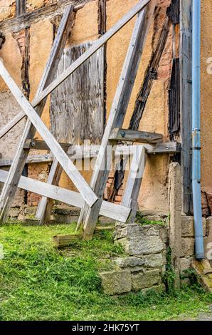 Una vecchia casa a graticcio dilapidata è tenuta da una struttura di sostegno. Foto Stock