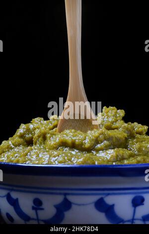 Pasta verde di curry thailandese in ciotola con cucchiaio di legno Foto Stock