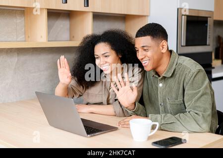 Coppia interrazziale che parla online, avendo video riunione sul portatile con la famiglia o gli amici. Uomo e donna multirazziale che salutano con la webcam, sorridendo e salutando. Conferenza online Foto Stock