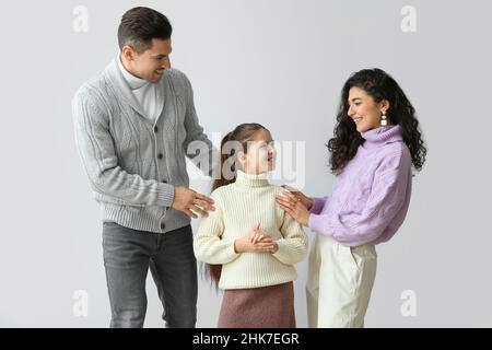 Bambina e i suoi genitori in maglioni caldi su sfondo chiaro Foto Stock