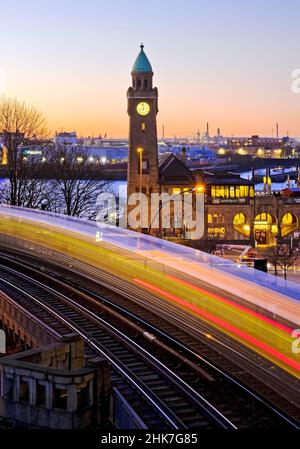 Suggestivi percorsi luminosi di movimento di ferrovia sopraelevata e torre dell'orologio all'alba, Landungsbruecken, St. Pauli, Amburgo, Germania Foto Stock