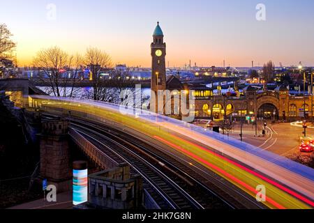 Suggestivi percorsi luminosi di movimento di ferrovia sopraelevata e torre dell'orologio all'alba, Landungsbruecken, St. Pauli, Amburgo, Germania Foto Stock