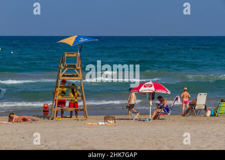 SPIAGGIA DI SAN JUAN, ALICANTE, SPAGNA - 29 AGOSTO 2016: Bagnini che sorvegliano la spiaggia mentre alcuni bagnanti godono di prendere il sole sulla riva in una calda giornata estiva Foto Stock