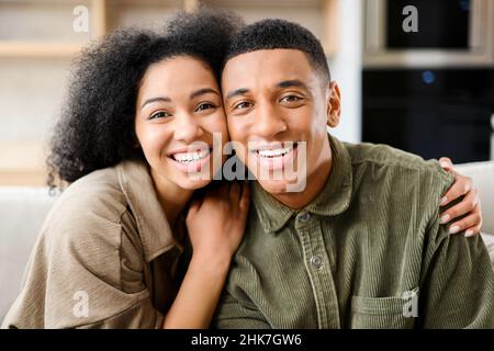 Felice insieme. Ritratto di amore giovane marito e moglie che si legano l'un l'altro in tenero abbraccia al soggiorno di accogliente appartamento in affitto casa propria. Sorridente coppia millennial risalente a casa Foto Stock