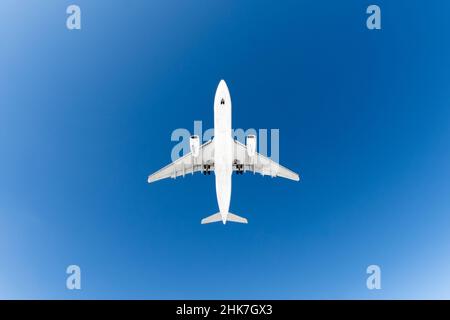 Aereo passeggeri. Vista esattamente dal basso, silhouette bianca contro il cielo blu Foto Stock
