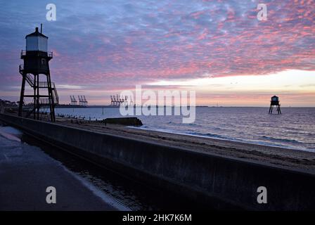 I colori dell'alba illuminano le nuvole del mattino sopra il faro di Dovercourt. Vista dall'ampio lungomare. Harwich & Dovercourt Bay, Essex, Regno Unito Foto Stock