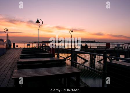 Un bellissimo tramonto sullo storico molo di Ha'penny in legno vittoriano a Harwich, nel Nord Essex, nel Regno Unito. La città di Shotley può essere vista attraverso il fiume. Foto Stock
