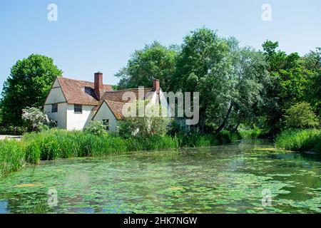 Willy Lott's Cottage a Flatford, gestito dal National Trust di Suffolk, Inghilterra. Vista in una giornata di sole con cielo blu chiaro e verde fogliame. Foto Stock