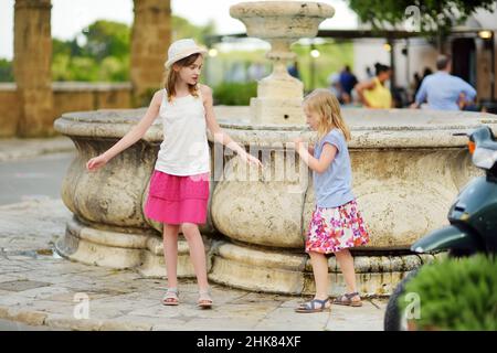 Giovani ragazze che esplorano la famosa città di Pitigliano, situata in cima a una cresta vulcanica di tufo, conosciuta come la piccola Gerusalemme. Belle città e ville italiane Foto Stock