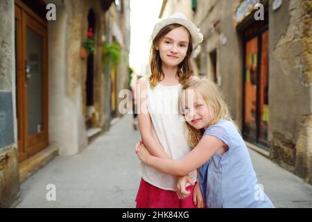 Giovani ragazze che esplorano la famosa città di Pitigliano, situata in cima a una cresta vulcanica di tufo, conosciuta come la piccola Gerusalemme. Belle città e ville italiane Foto Stock