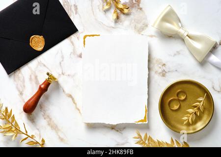 Elegante modello di biglietto d'invito per matrimoni. Flat lay, vista dall'alto, lussuosa cancelleria da matrimonio posta su sfondo dorato in marmo. Foto Stock