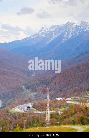 Verdi pendii di montagna con vette innevate sotto un cielo nuvoloso. Rosa Khutor, Sochi, Russia, 2021 Foto Stock
