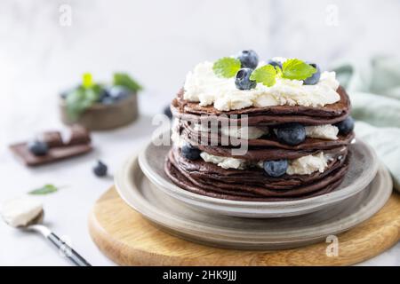 Festeggiamo la giornata di Pancake. Deliziose banane americane fatte in casa frittelle di cioccolato con mirtilli e ricotta su un tavolo di marmo. Foto Stock