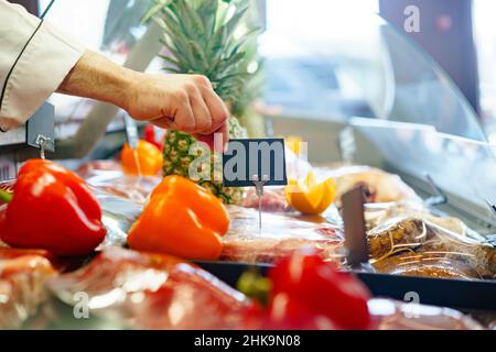 Maschio mano mettere prezzo tag in mostra di carne in negozio, spazio copia Foto Stock