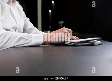 Businessman ha aperto il pianificatore e sta prendendo le note di lavoro o scrivendo l'ordine del giorno. Uomo mani primo piano. . Foto di alta qualità Foto Stock