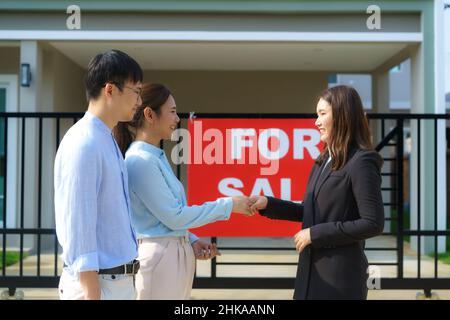 Felice coppia asiatica alla ricerca della loro nuova casa e agitare le mani con broker immobiliare dopo un accordo. Giovane coppia handshaking agente immobiliare dopo Foto Stock