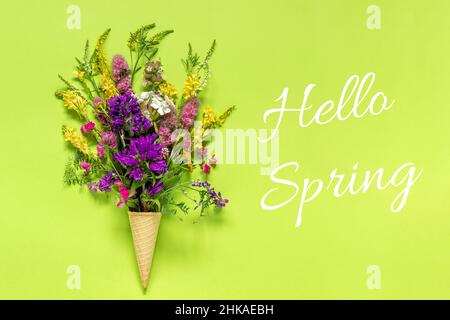 Text Hello Primavera e campo bouquet fiori colorati in cialda gelato cono su carta verde sfondo Creative Flat lay Top view concept springtime. Foto Stock