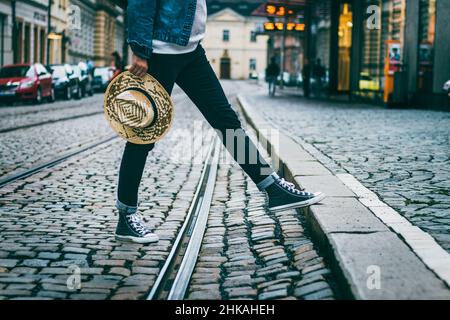 La donna indossa sneakers e cammina per la strada. Donna in abiti casual a piedi nella città vecchia. Foto Stock