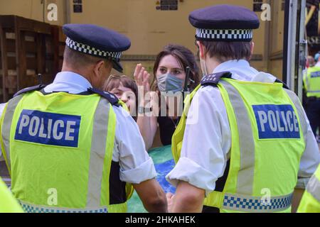Gli ufficiali di polizia parlano con un dimostratore che si è attaccato ad un furgone che blocca le strade durante una protesta della ribellione di estinzione a Cambridge Circus. Londra, Regno Unito 24th agosto 2021. Foto Stock