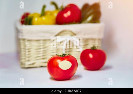 Apporre sul pomodoro l'etichetta del prodotto a basso tenore di carbonio o dell'etichetta del prodotto a basso tenore di carbonio. Cestino di verdure sullo sfondo. Prodotti agricoli biologici dal mercato locale. Alta qu Foto Stock