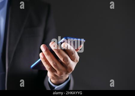 Primo piano della mano del giovane uomo utilizzando smartphone isolato su nero Foto Stock