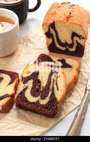 Deliziosa torta di marmo fatta in casa su sfondo di marmo bianco, a fette servita con tè Foto Stock