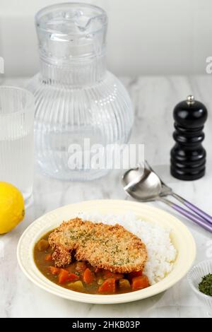 Curry di Cutlet di pollo con riso - cucina giapponese. Vista dall'alto su piatto in ceramica tavolo in legno nero con patate e carote Foto Stock