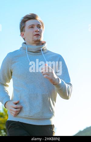 L'uomo che fa jogging nella natura rurale durante la splendida giornata estiva. Sport fitness modello caucasico etnia formazione all'aperto. Foto Stock