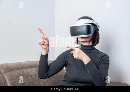 Teen girl che utilizza il visore vr è nello spazio informatico della realtà virtuale. Il concetto di metaverse, realtà virtuale, universo sociale virtuale. Te digitale futuro Foto Stock