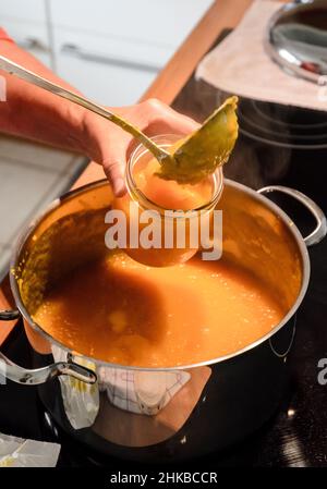 Preparazione a mano di marmellata d'arancia fresca fatta in casa in cucina Foto Stock