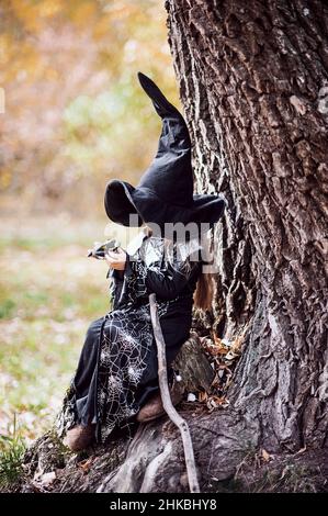 Bella ragazza strega. Bambina in cui costume celebrare Halloween all'aperto e divertirsi. Trucchi o trattamenti per i bambini. Foto Stock