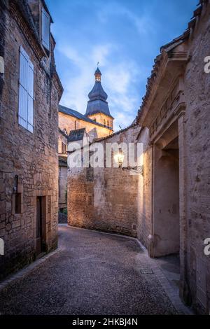 Stretta strada acciottolata in pietra a Sarlat la Caneda all'alba con lampada di strada e Sarlat Cathederal sullo sfondo Sarlat Dordogna Francia Foto Stock