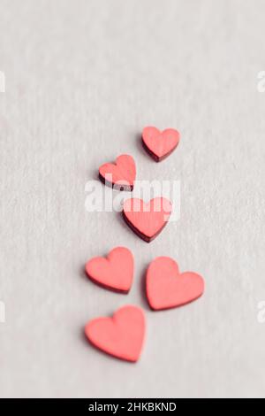 Cuori di legno rosso su sfondo beige, cornice verticale, concetto d'amore minimalista Foto Stock