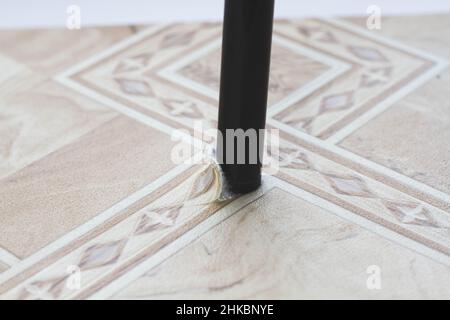 Linoleum strappato. Gamba sedia e linoleum lacerato. Foro nel linoleum. Sedia sul pavimento. Tracce di utilizzo di rivestimenti per pavimenti. Resistenza all'usura. Protezione agai Foto Stock