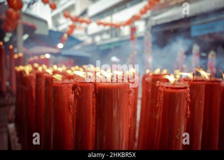 Candele rosse visto bruciare fuori di un tempiale.il Capodanno lunare a Bangkok quest'anno è un affare più solenne che negli anni precedenti. Il governo aveva tecnicamente cancellato grandi celebrazioni, ma a Chinatown, una troupe di ballerini di leoni rallentò il traffico in arrivo su Yaowrat Road. Su una strada laterale a Wat Lokanukroh, l'unica eccitazione per il giorno è stato lo scoppio di un piccolo fuoco causato quando le grandi candele rosse illuminate crollarono l'una sull'altra; i custodi si precipitarono per un estintore. Molti Thais di discendenza cinese continuarono ad eseguire riti e preghiere al santuario senza disturbi. Foto Stock